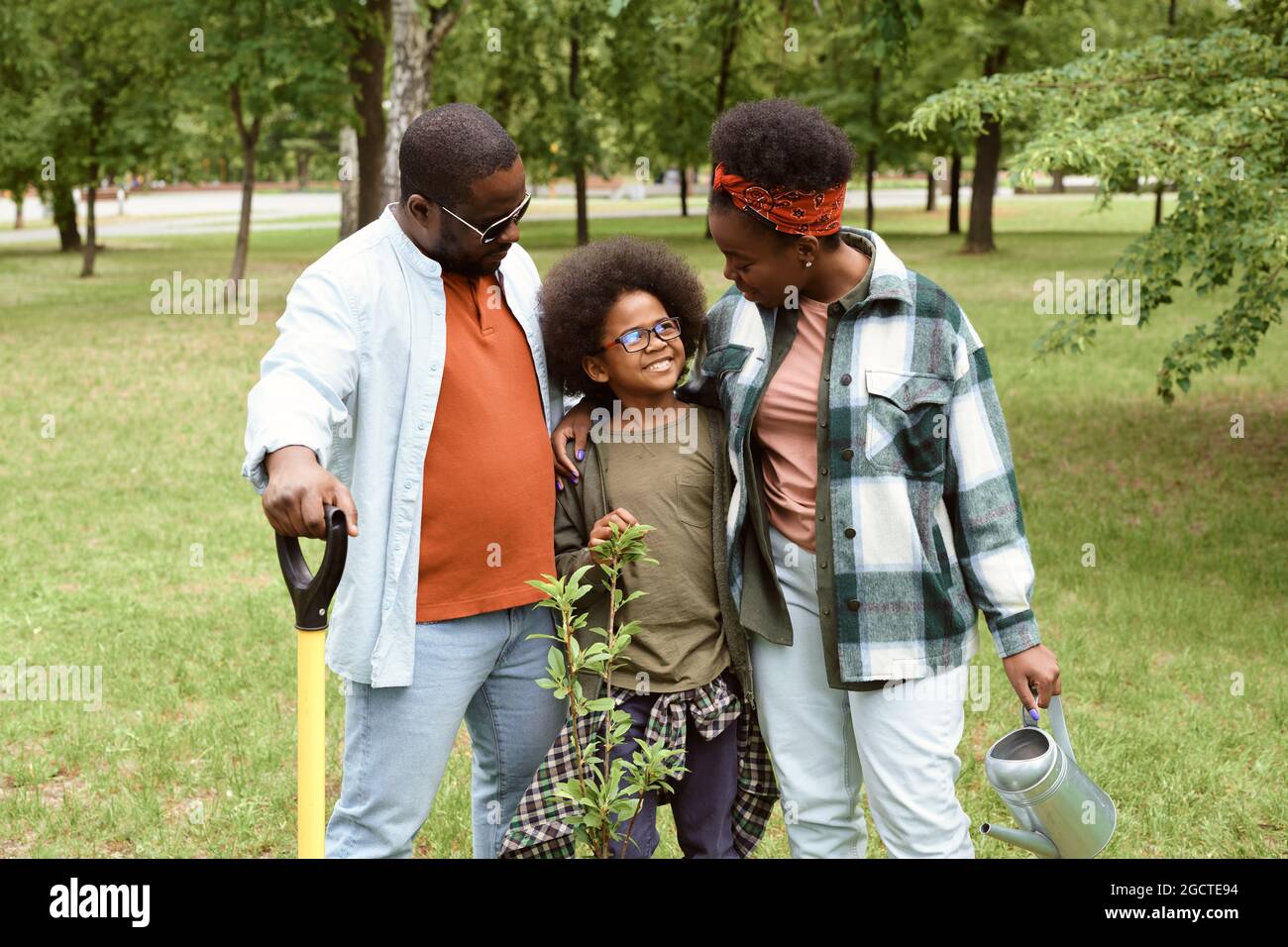 Affettuosa famiglia africana che cammina lungo il prato verde in un grande parco Foto Stock