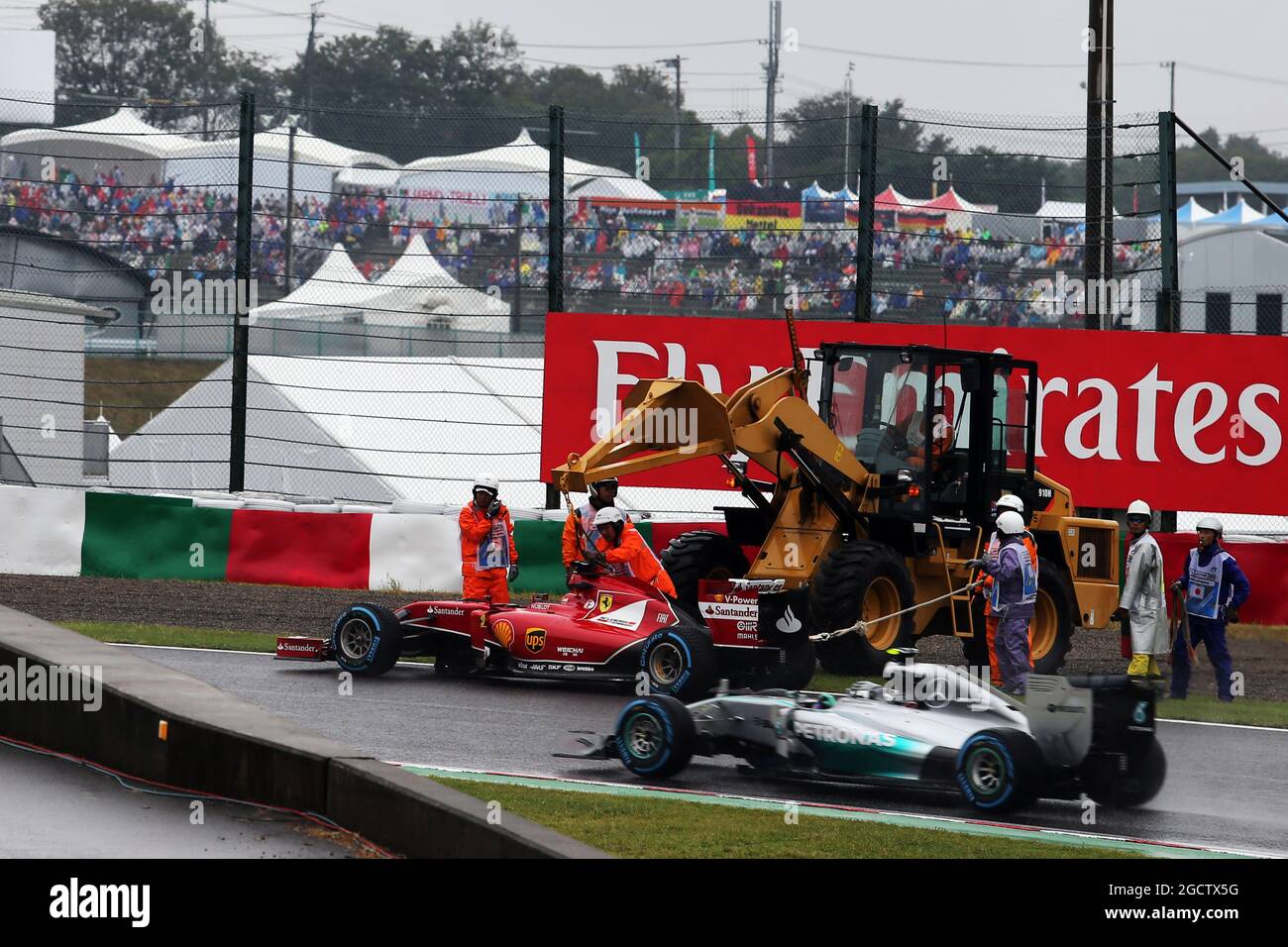Nico Rosberg (GER) Mercedes AMG F1 W05 supera la Ferrari F14-T colpita di Fernando Alonso (ESP) Ferrari, che viene rimossa dai marescialli utilizzando un digger. Gran Premio del Giappone, domenica 5 ottobre 2014. Suzuka, Giappone. Foto Stock