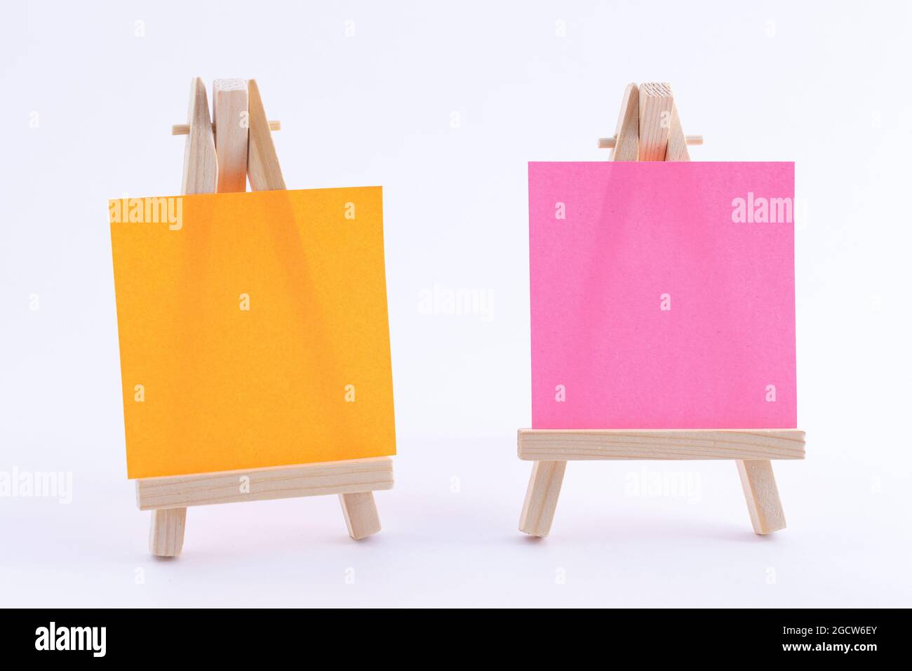Due vasi in legno in miniatura con tela quadrata colorata vuota o carta Memo - Mockup. Mini supporto in legno con tavola da disegno pulita su sfondo bianco, spazio per la copia Foto Stock