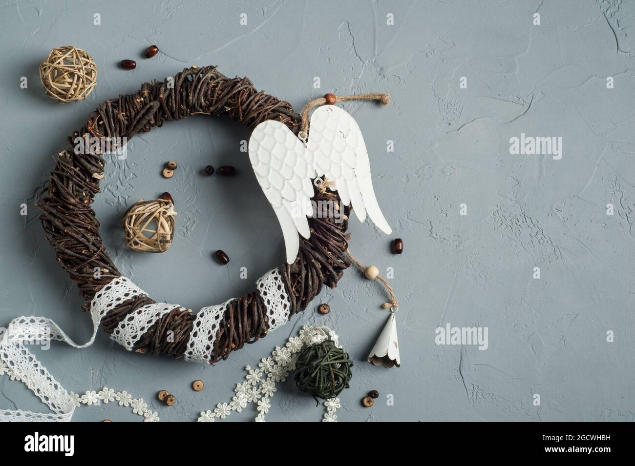 Decorazione di Natale con anello di vimini, lacci, angelo ali giocattolo su fondo di cemento. Matrimonio, xmas struttura ruvida posa piatta Foto Stock