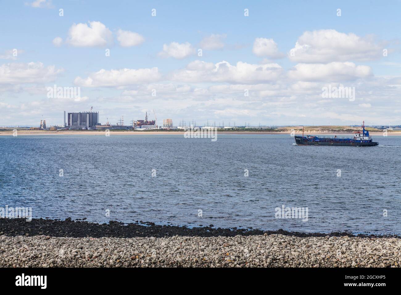 La centrale nucleare di Hartlepool e le piattaforme petrolifere decommissionate al porto di Seaton, viste dalla South Gare, Redcar, Inghilterra, UK.drager si avvicinano a Teesport Foto Stock