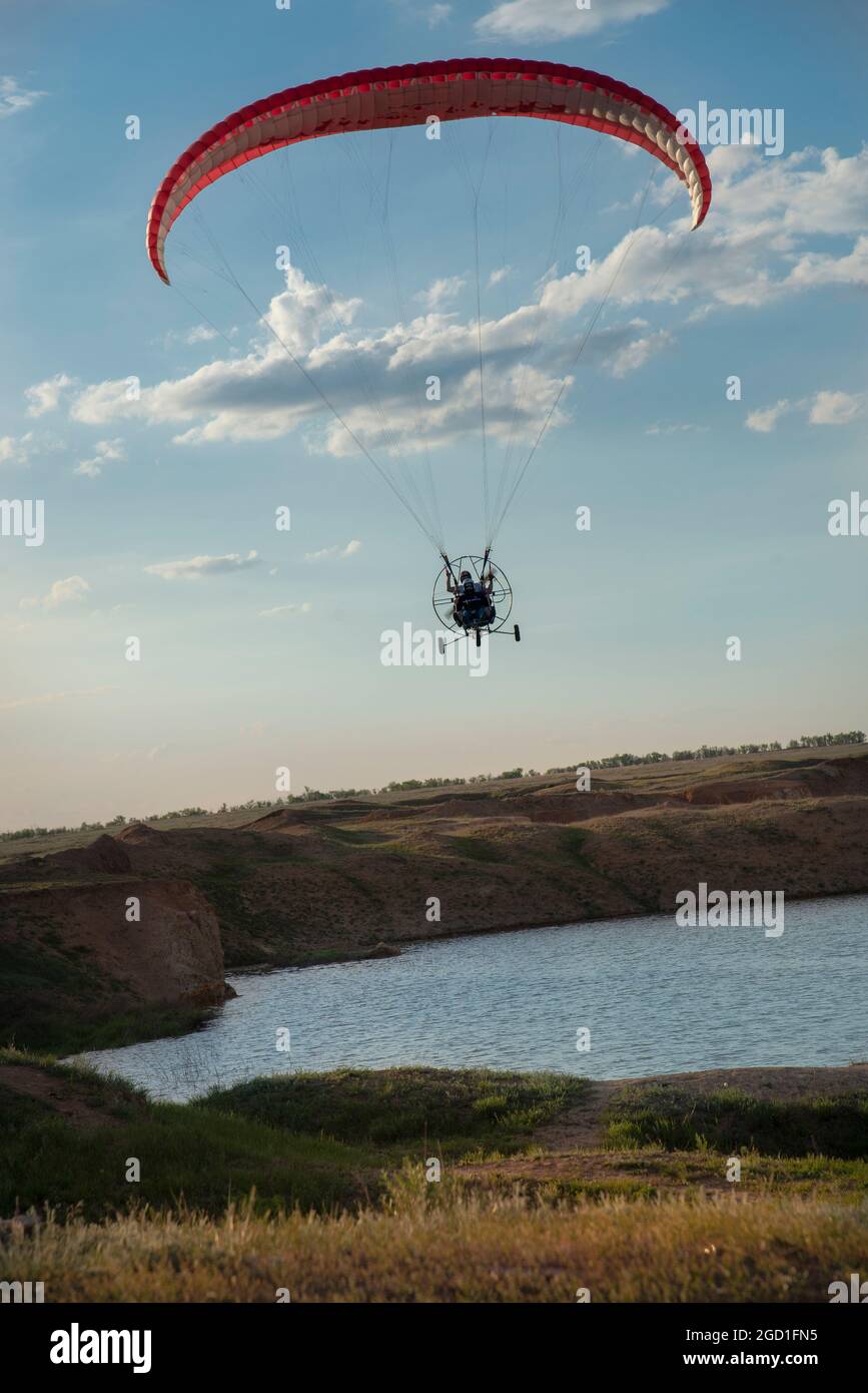 Il parapendio vola sul fiume e il campo verso di voi. Volare su un parapendio motorizzato. Il concetto di sport estremi Foto Stock
