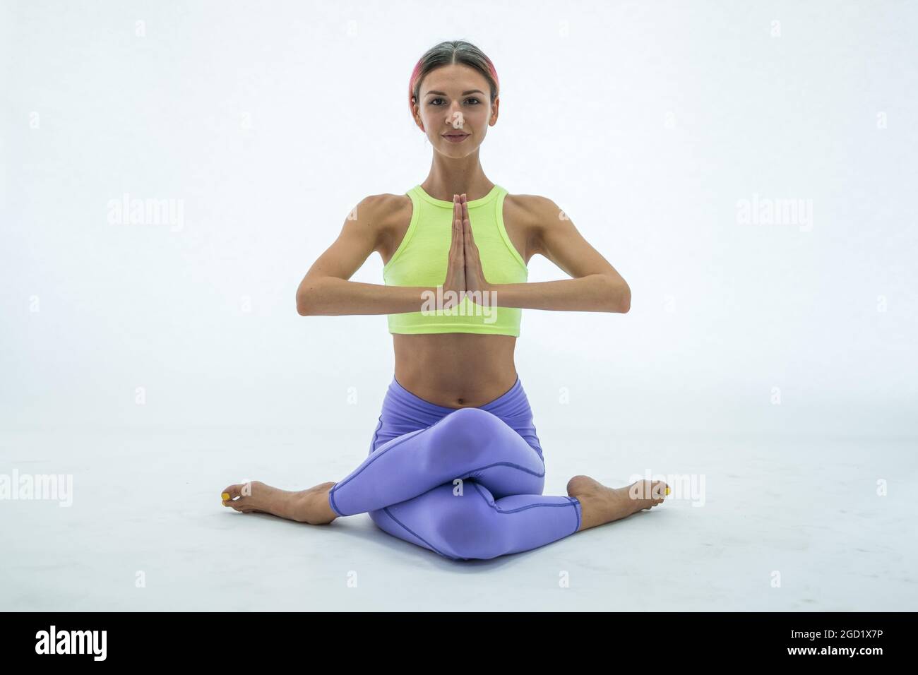 Giovane bella donna yoga in posa isolata su bianco. Foto studio. Caucasica. Abbigliamento sportivo colorato. Guardando la fotocamera con spazio per la copia. Alta qualità Foto Stock