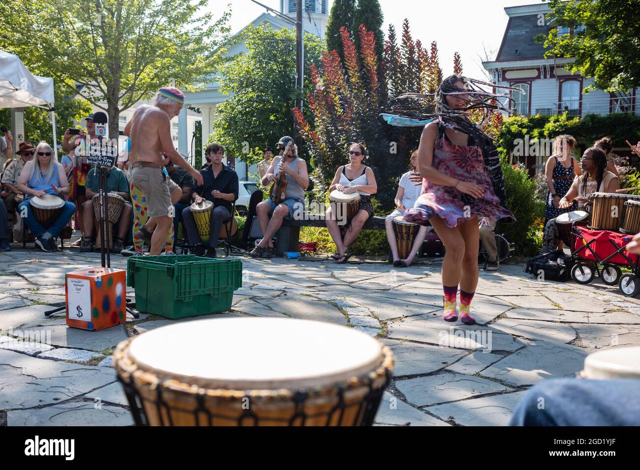 Woodstock, NY, USA - 8 agosto 2021: Un uomo e una donna ballano ai suoni di un circolo di tamburi della comunità tenuto al Village Green durante il pomeriggio estivo Foto Stock