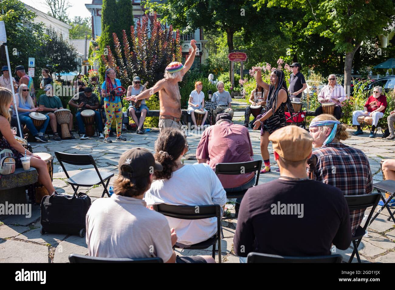 Woodstock, NY, USA - 8 agosto 2021: Un uomo e una donna ballano ai suoni di un circolo di tamburi della comunità tenuto al Village Green durante il pomeriggio estivo Foto Stock