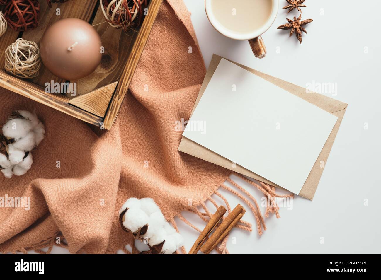 Accogliente tavolo da scrivania autunnale con lettera romantica, sciarpa, tazza da caffè, cotone, candela e decorazioni su bianco. Disposizione piatta, vista dall'alto Foto Stock