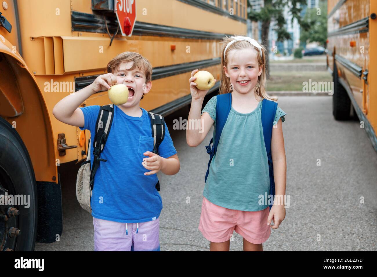 Bambini ragazzi e ragazze studenti amici mangiare mele snack sano da scuola bus giallo all'aperto. Istruzione e ritorno a scuola nel mese di settembre. Compagno di classe Foto Stock