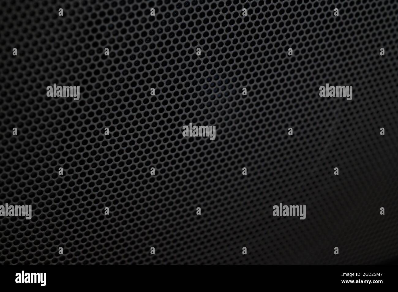 Foto closeup di una piastra metallica nera perforata con una griglia di fori rotondi utilizzata su un amplificatore portatile Blackstar Fly per chitarra elettrica. Foto Stock