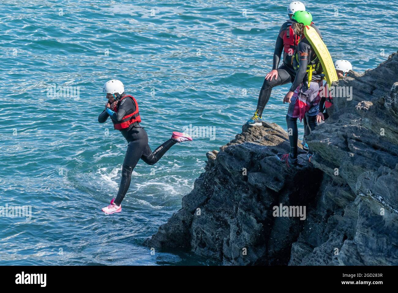 I vacanzieri saltano dalle rocce costellando con una guida su Towan Head a Newquay in Cornovaglia. Foto Stock