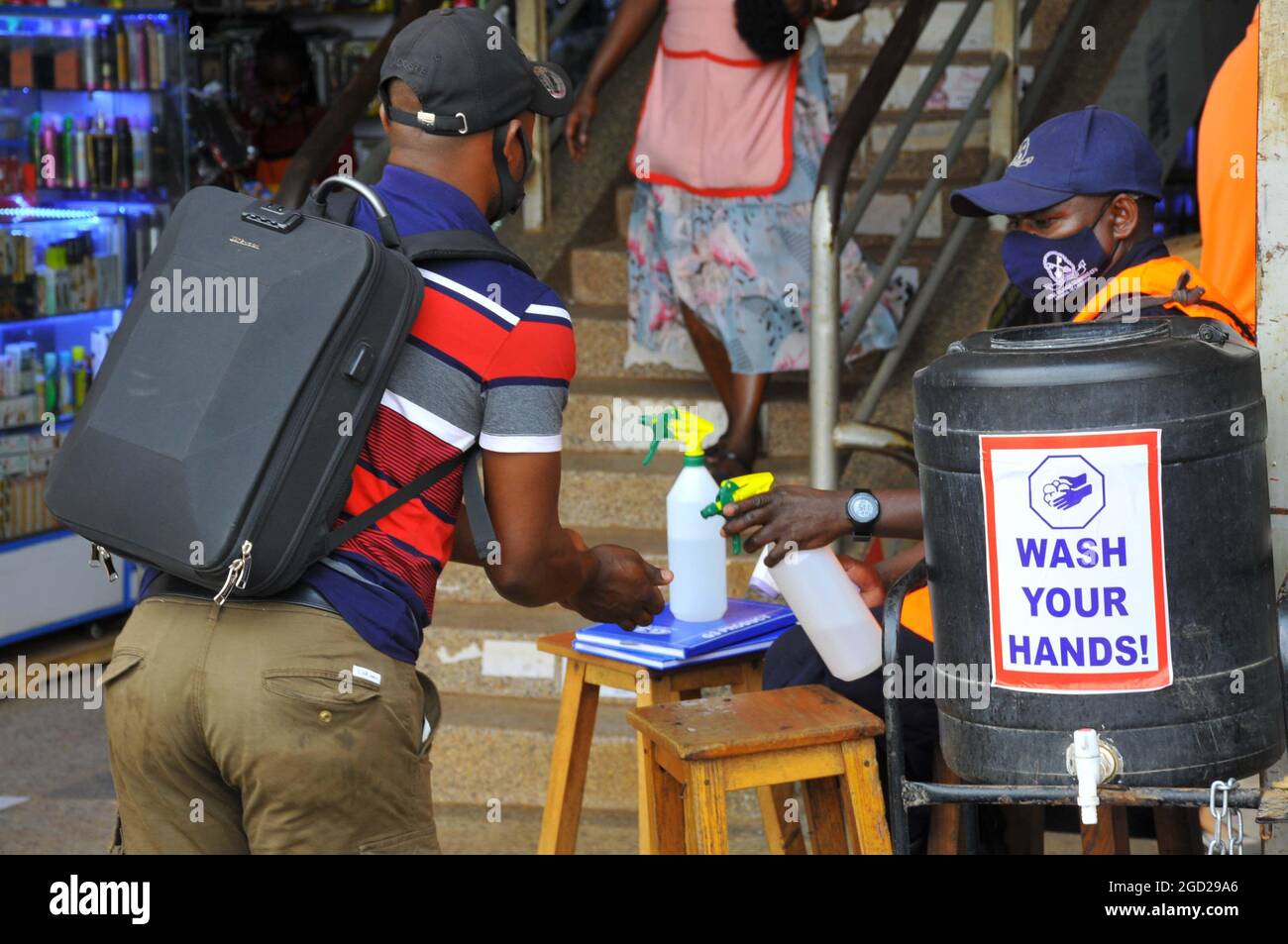 Un uomo che igienizza le mani prima di entrare in un negozio. Il governo ha messo a punto linee guida sanitarie per combattere il Covid-19. Uganda. Foto Stock