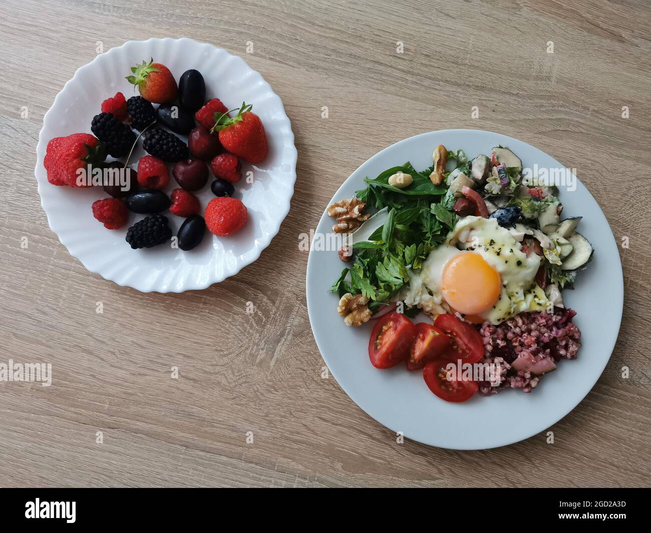 Una sana e gustosa colazione estiva. Uova sode, semole di grano saraceno, verdure colorate, noci e bacche Foto Stock