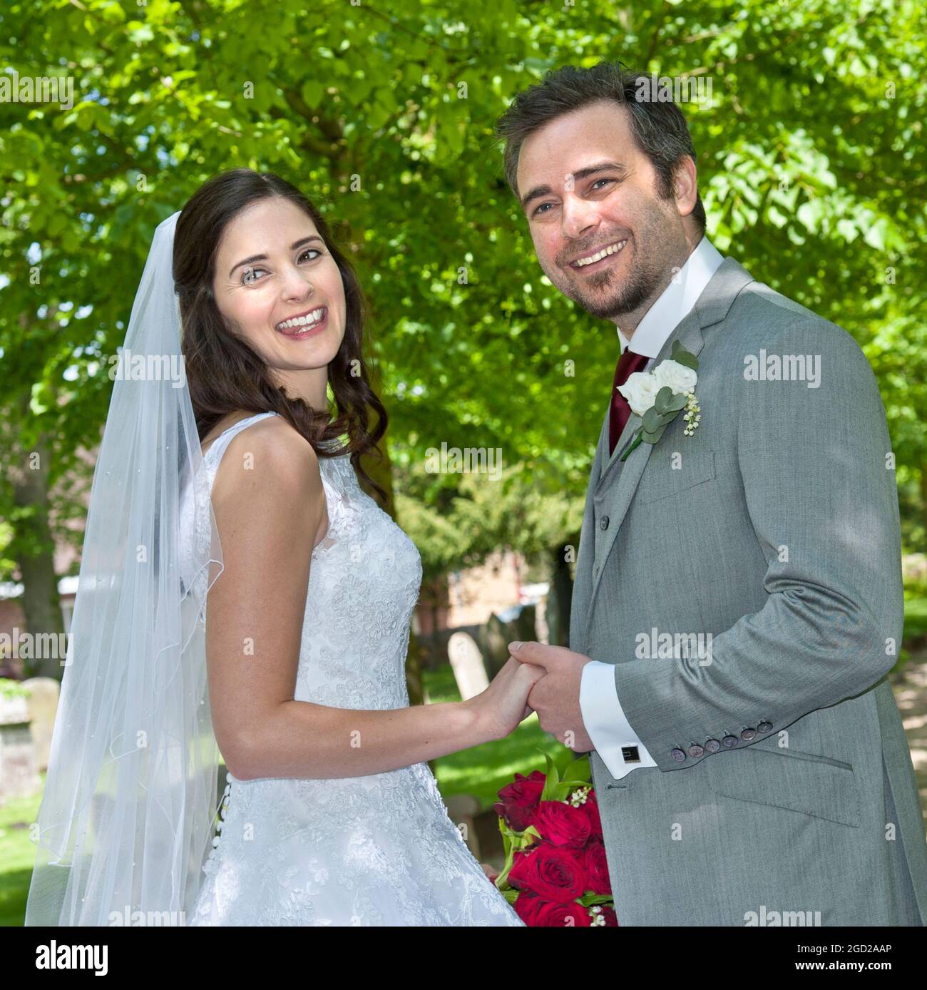 IL SENTIERO DELLA CHIESA DELLO SPOSO SPOSA IL TRADIZIONALE MATRIMONIO BIANCO FELICE e attraente giovane sposa tradizionale appena sposata camminando lungo il sentiero alberato Foto Stock