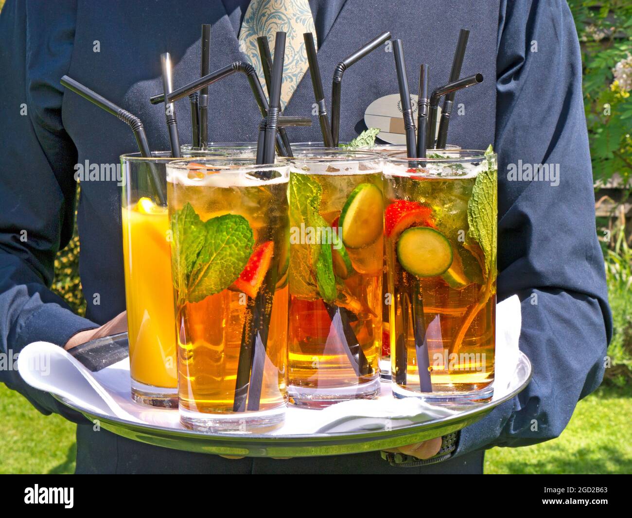 AL FRESCO PIMMS BEVANDE HOTEL BICCHIERI cameriere servizio estate menta frutta tazza vassoio bevande all'aperto albergo di lusso terrazza giardino all'aperto evento all'aperto Foto Stock