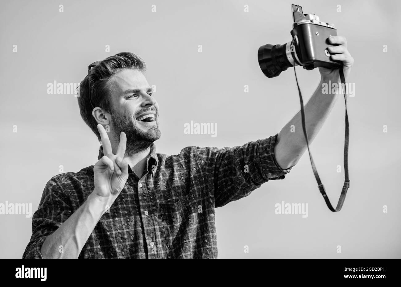 Blogger tiro vlog. Tempo di vacanza. Bella blogger ragazzo viaggiatore fotocamera retrò. Guy Outdoors cielo blu sfondo. Concetto di fotogiornalista. Viaggi Foto Stock