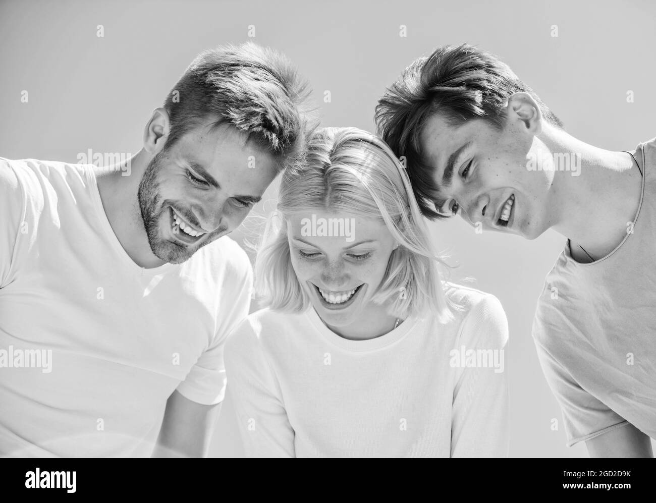 I giovani spensierati si ritrovano insieme. Vedi qualcosa di adorabile. Felicità. Cosa c'è. Gruppo persone entusiasta guardare giù. Donna e uomini cielo felice sfondo Foto Stock
