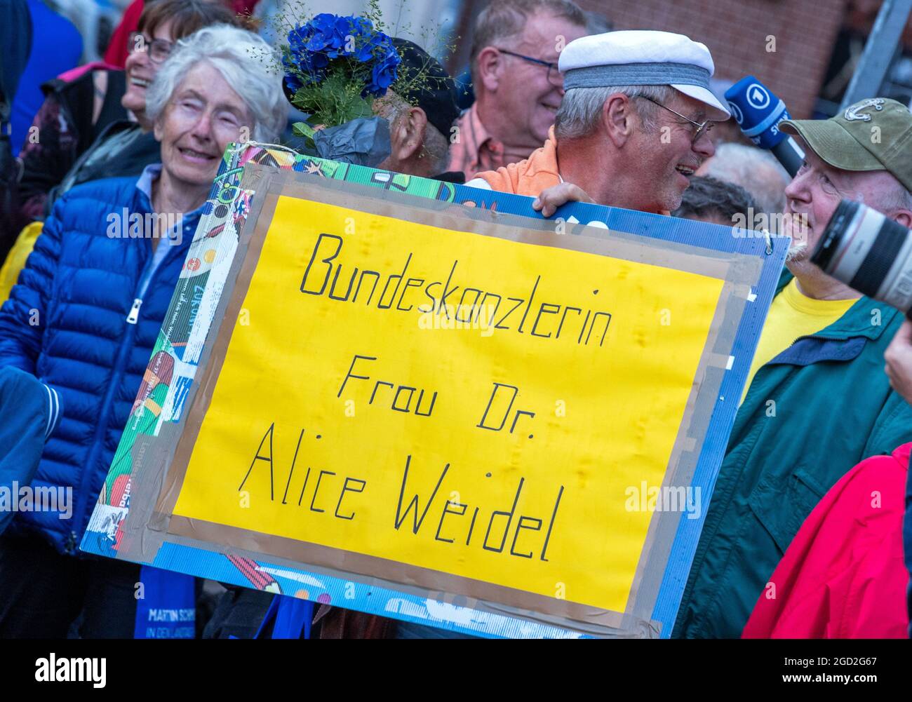 Schwerin, Germania. 10 agosto 2021. Un sostenitore dell'AFD ha un poster con la scritta "Cancelliere Dr. Alice Weidel" e si trova di fronte al palco all'inizio del tour della campagna dell'AFD. Il partito sta entrando nella campagna elettorale con lo slogan 'Germania. Ma normale.' nella campagna elettorale. Credit: Jens Büttner/dpa-Zentralbild/dpa/Alamy Live News Foto Stock