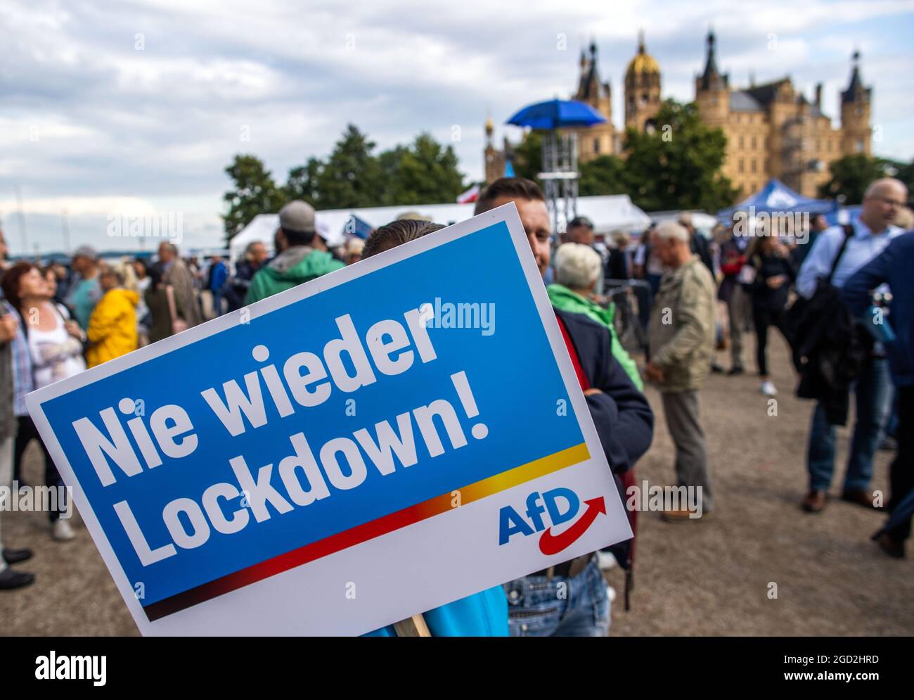 Schwerin, Germania. 10 agosto 2021. Un sostenitore dell'AFD si trova di fronte al castello di Schwerin con un poster che recita "mai più blocco" all'inizio del tour della campagna dell'AFD. Il partito sta facendo campagna con lo slogan 'Germania. Ma normale.' nella campagna elettorale. Credit: Jens Büttner/dpa-Zentralbild/dpa/Alamy Live News Foto Stock
