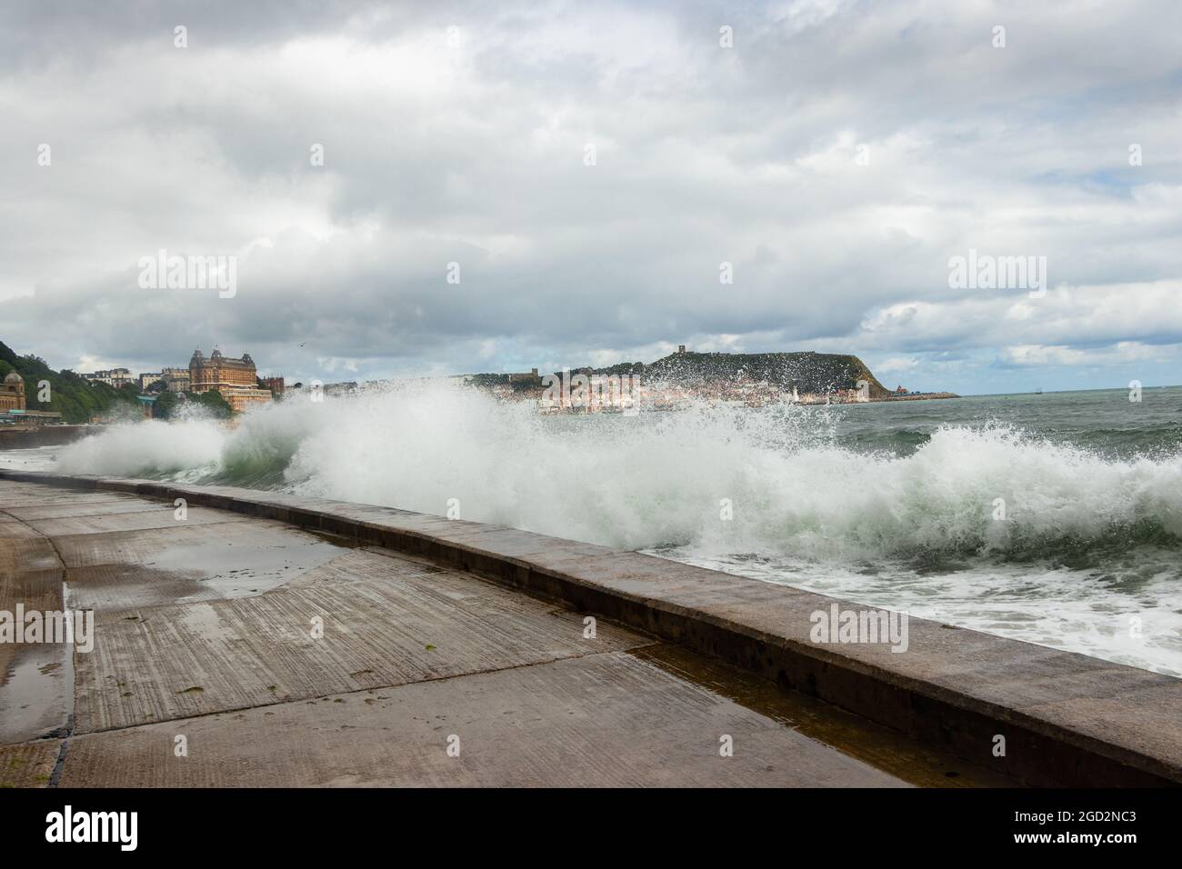 Onde che si infrangono contro le difese del mare con il Grand Hotel sullo sfondo dello Scarborough Yorkshire Foto Stock