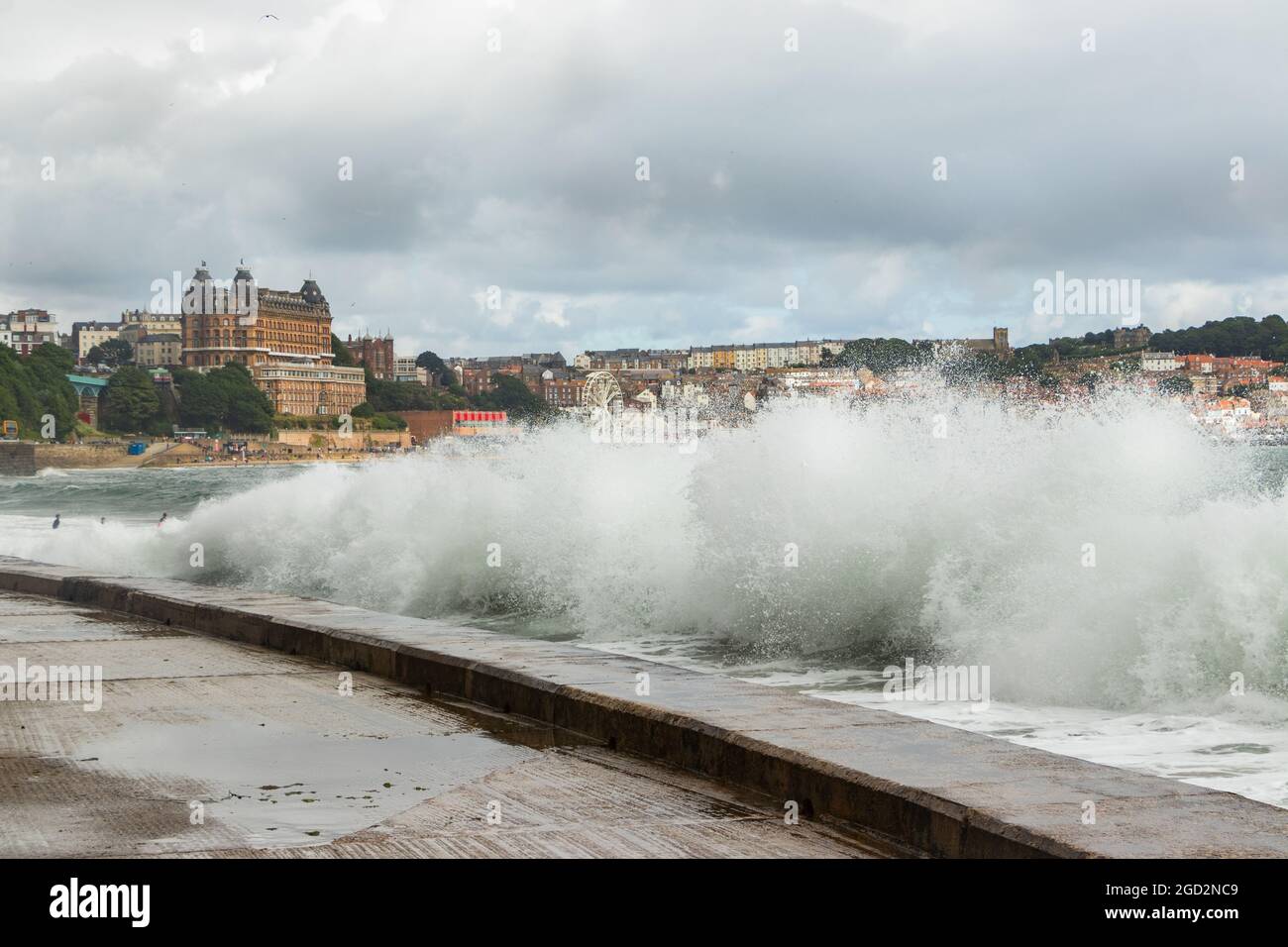 Onde che si infrangono contro le difese del mare con il Grand Hotel sullo sfondo dello Scarborough Yorkshire Foto Stock