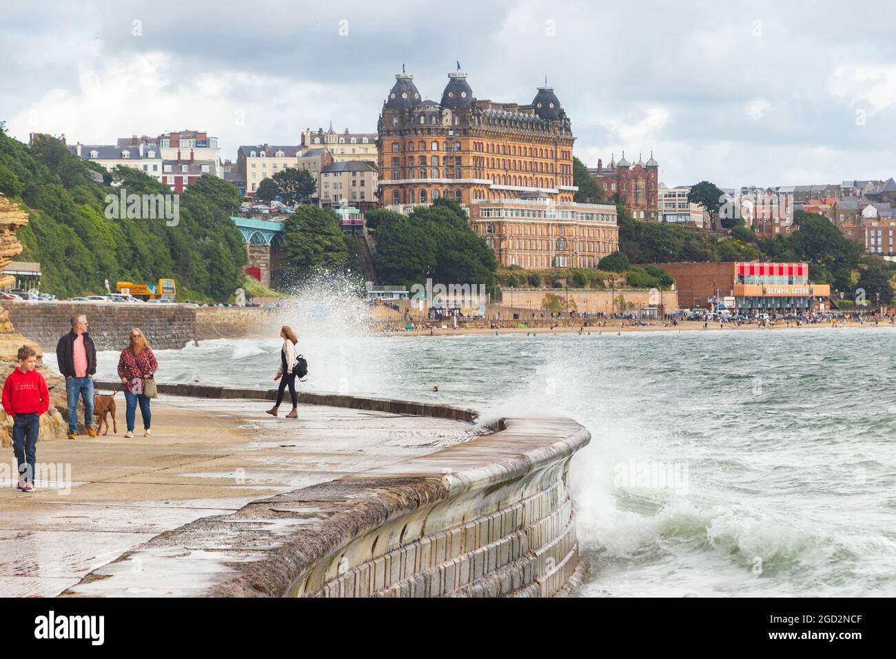 Onde che si infrangono contro le difese del mare con il Grand Hotel sullo sfondo dello Scarborough Yorkshire Foto Stock