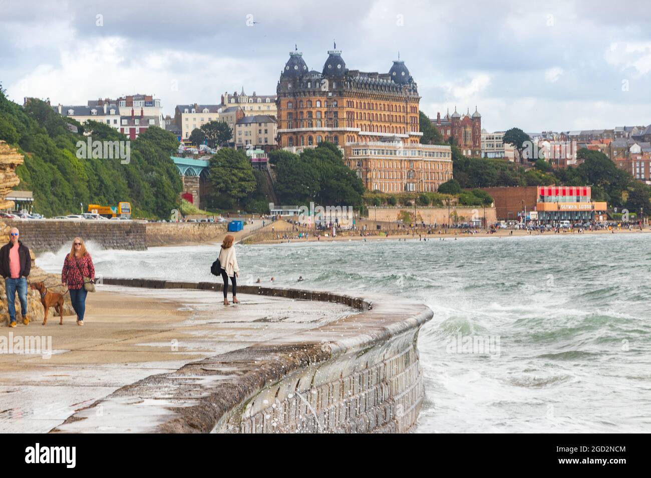 Onde che si infrangono contro le difese del mare con il Grand Hotel sullo sfondo dello Scarborough Yorkshire Foto Stock