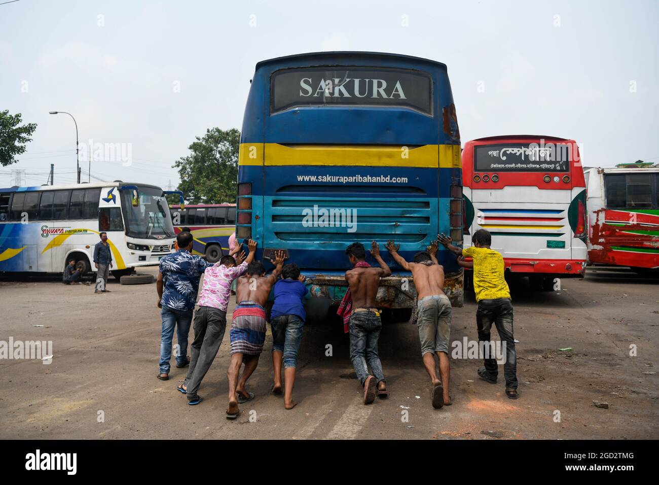 Dhaka, Bangladesh. 10 agosto 2021. I lavoratori dei trasporti spingono un autobus per aiutarlo a iniziare mentre i trasporti pubblici riprendono dopo un periodo di blocco al terminal degli autobus di Gottoli a Dhaka.dopo un blocco, i trasporti pubblici riaprono domani in tutto il paese in Bangladesh. (Foto di Piyas Biswas/SOPA Images/Sipa USA) Credit: Sipa USA/Alamy Live News Foto Stock