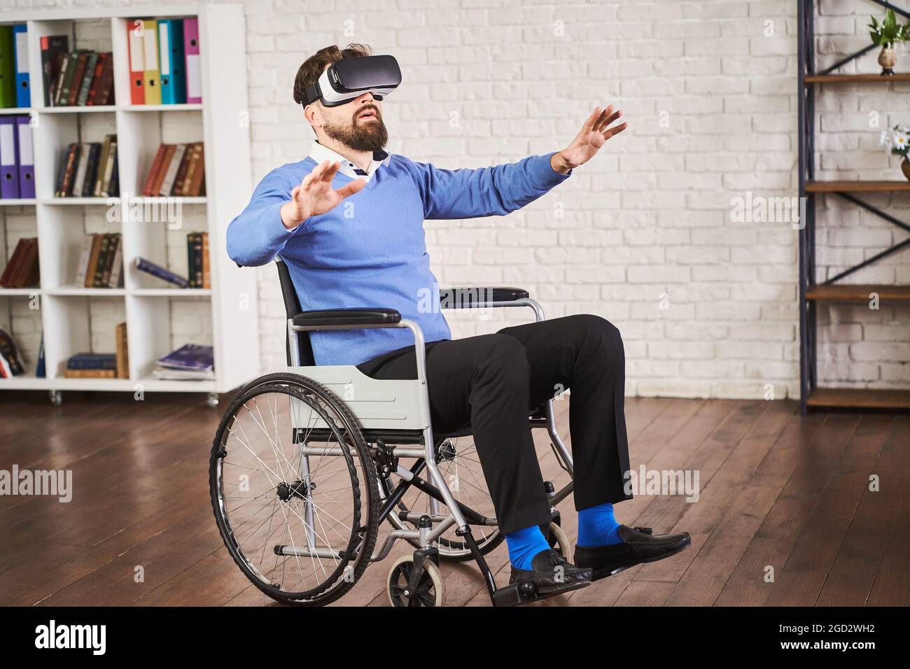 Uomo seduto su una sedia a rotelle e che utilizza un visore VR Foto Stock