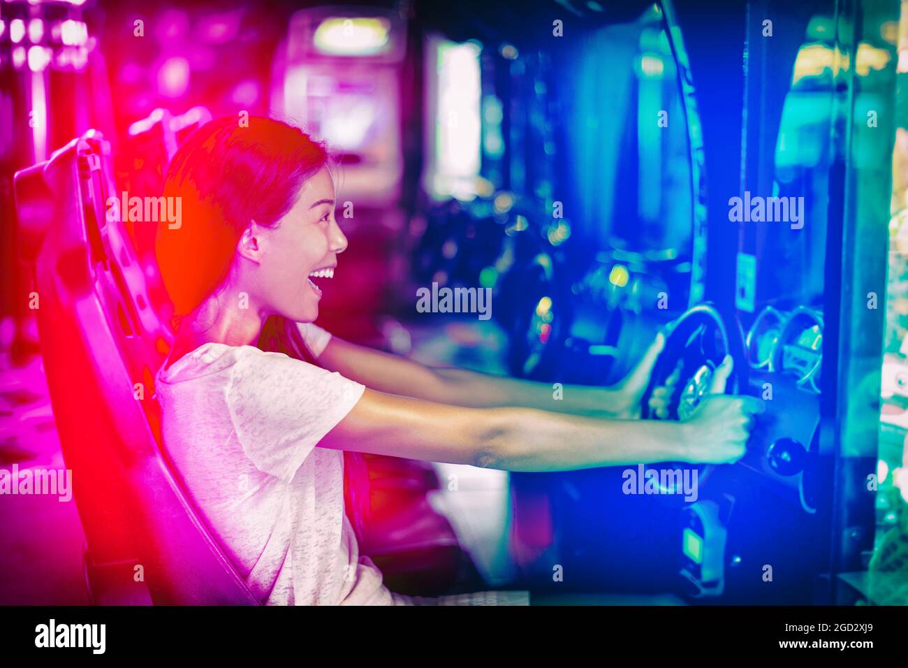 Gioco giapponese cyber cafe ragazza gamer divertirsi con il gioco. Guida corsa auto gioco divertente Asian donna giocare videogioco sport virtuale auto arcade macchina. Foto Stock