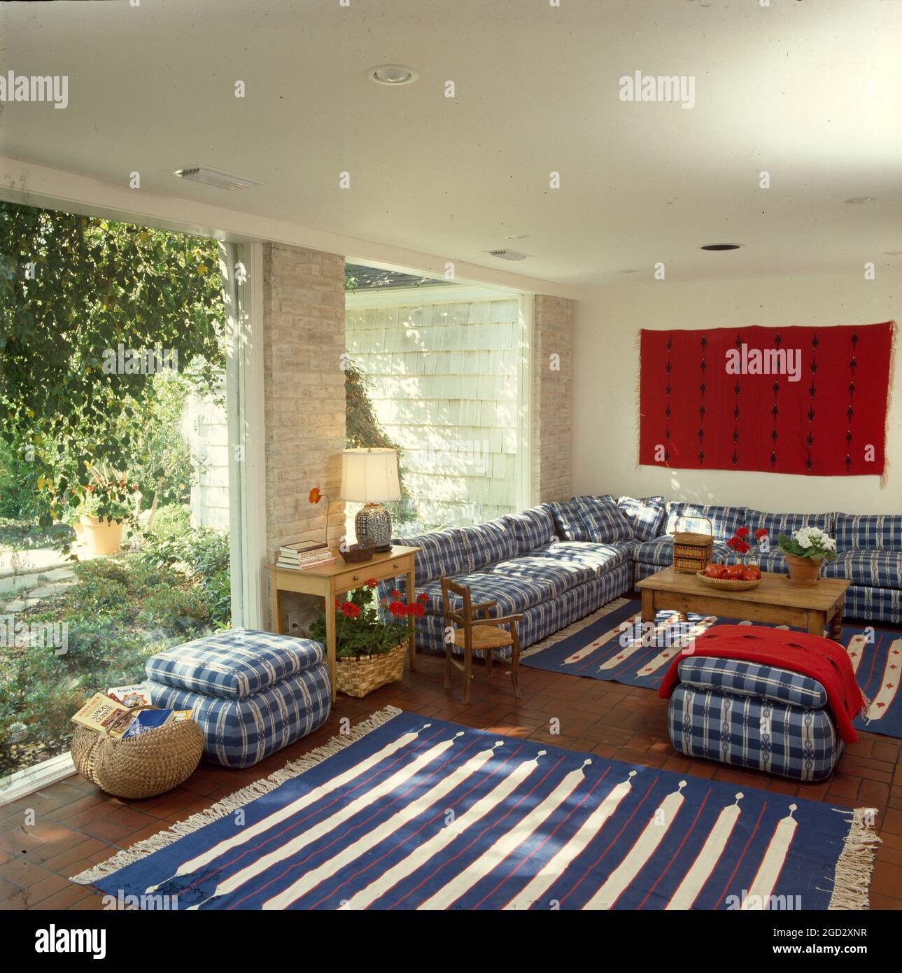 Soggiorno di design con tessuti blu e bianchi su divano e sedie che si affacciano sul patio soleggiato. Foto Stock