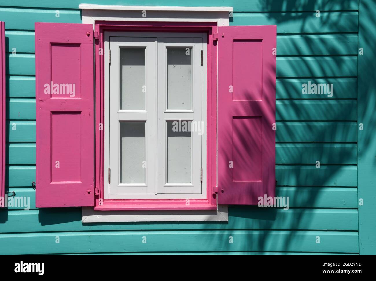 Vibrante edificio e finestra color turchese caraibico con persiane rosa Foto Stock