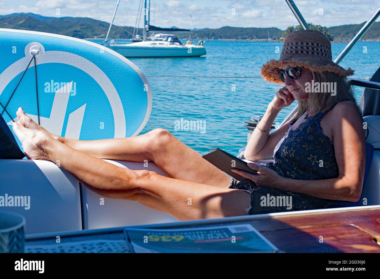 Donna rilassante lettura kindle in cabina di pilotaggio yacht. Foto Stock