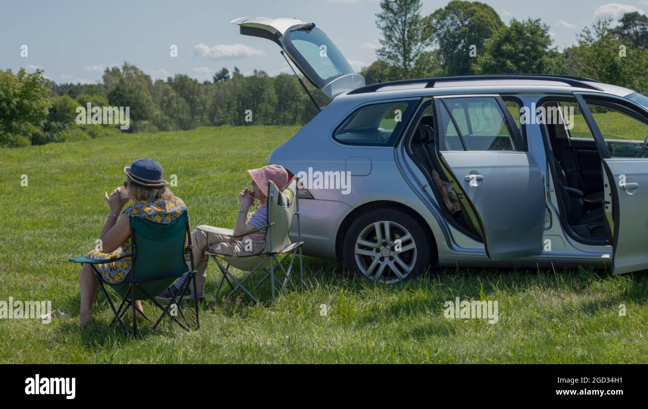 due femmine sedettero in un campo bevendo tè al sole Foto Stock