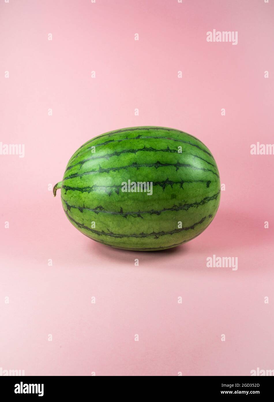 Cocomero fresco su sfondo rosa pastello alla moda. Frutta tropicale minima e concetto estivo. Foto Stock