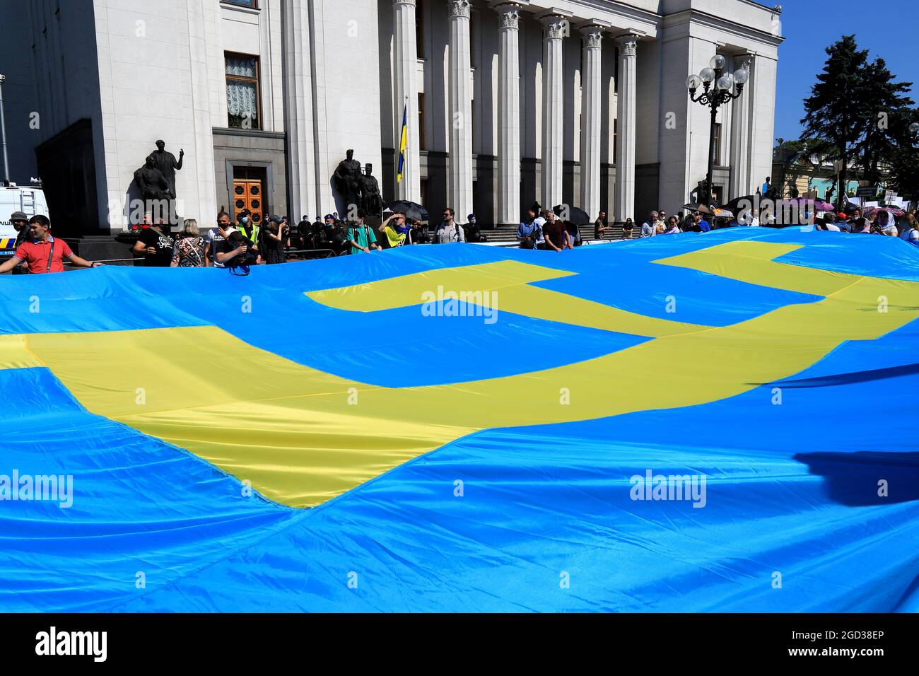 Un'enorme bandiera Tatar della Crimea fu sfurtata vicino alla Verkhovna Rada dell'Ucraina. I Tatari Crimea detengono una grande bandiera blu con un emblema di tanghi giallo vicino alla U. Foto Stock