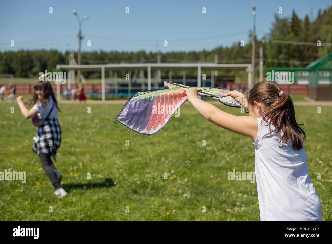 I bambini volano un aquilone. Due ragazze stanno provando a lanciare una figura dell'uccello che si aggira nel vento. Foto Stock