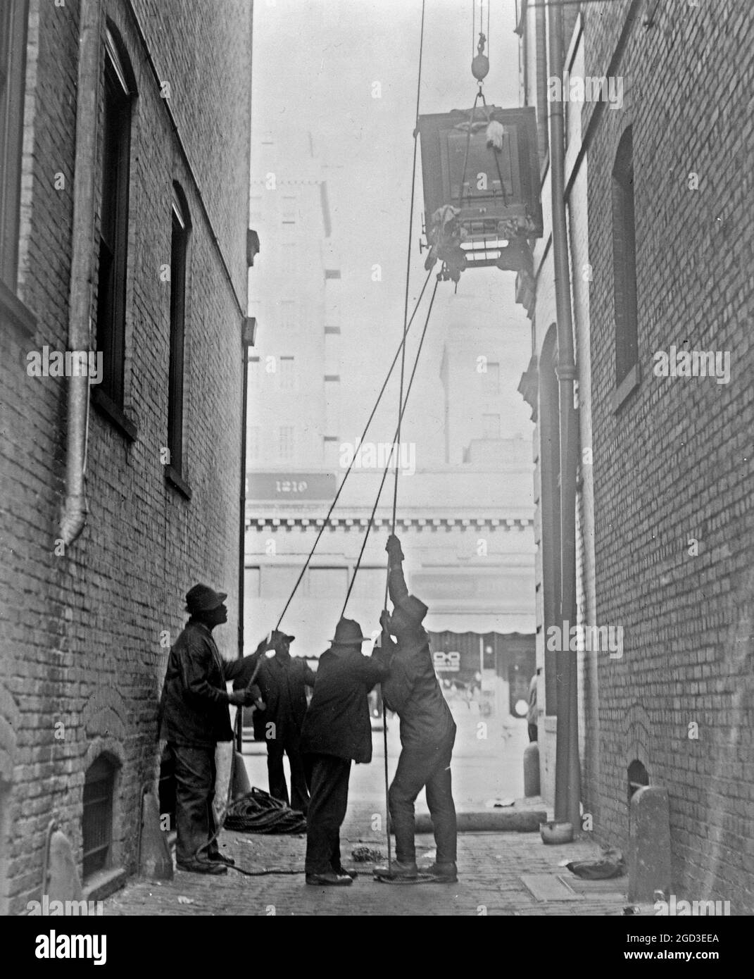 Tre uomini afroamericani che sollevano un pezzo di attrezzatura, con blocco e paranco, alla Standard Engraving Company ca. 1909 Foto Stock