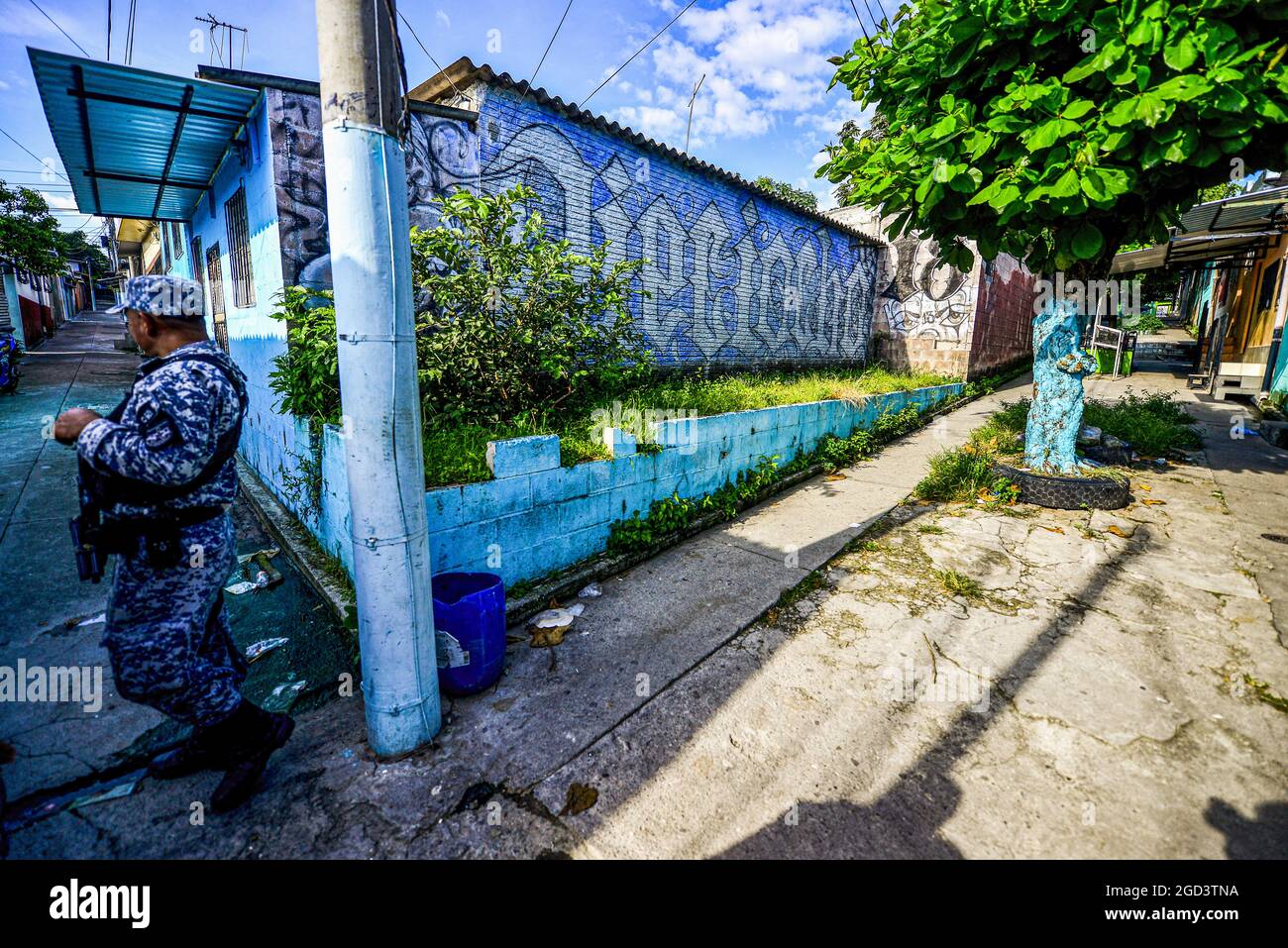 Un ufficiale di polizia si trova sulla guardia accanto a un muro che mostra un murale diciottesimo gruppo di strada durante un'operazione di ricerca per i membri della banda. La polizia nazionale di El Salvador esegue operazioni di polizia presso la comunità di Cumbres de San Bartolo, dove i membri della banda del Barrio 18 mantengono il controllo territoriale. Gli agenti di polizia hanno iniziato a utilizzare droni e termografia come parte della loro risposta contro i criminali organizzati. (Foto di Camilo Freedman / SOPA Images/Sipa USA) Foto Stock