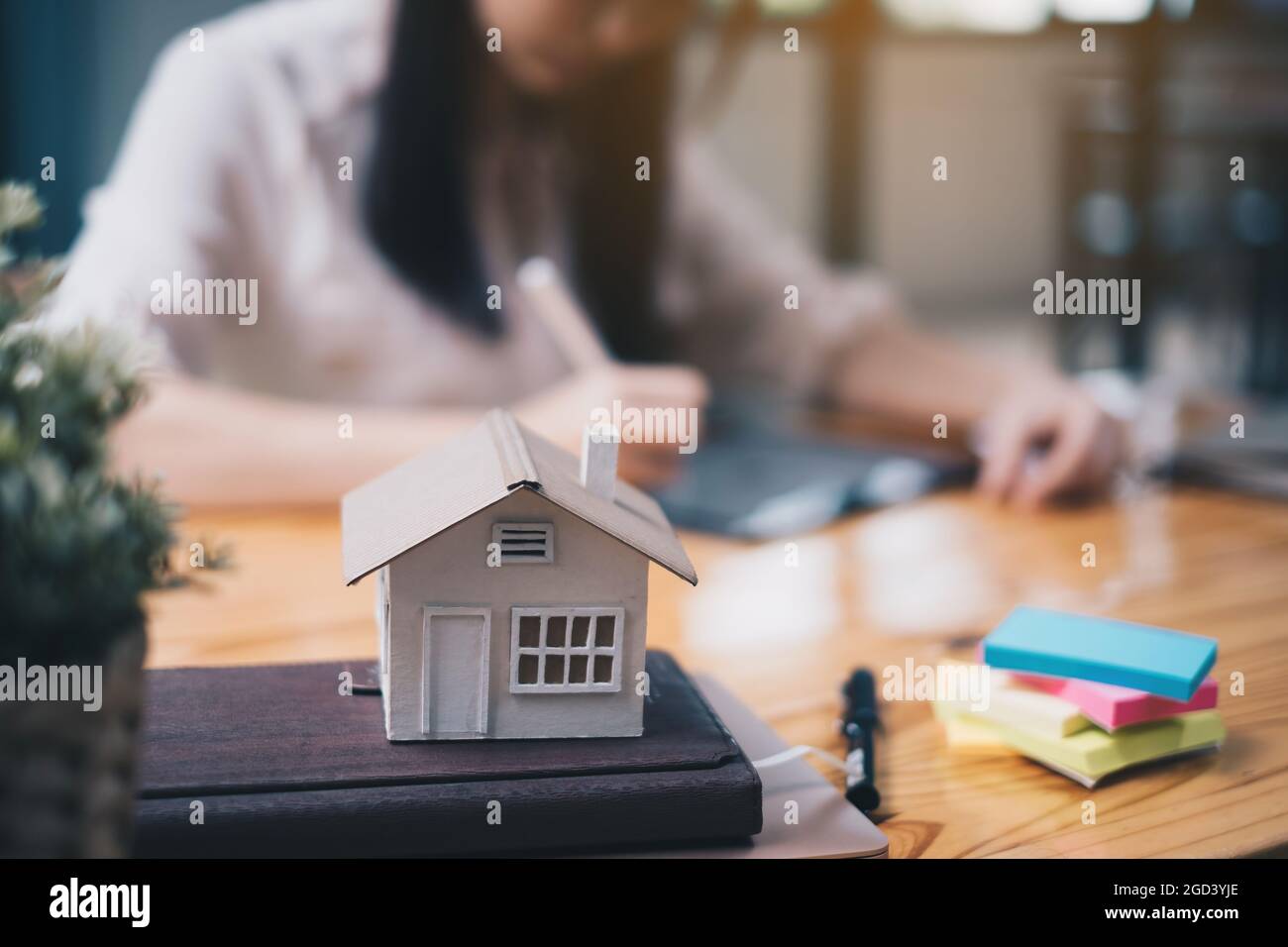 Donna architetto che utilizza un'applicazione tablet digitale per disegnare a mano una casa di design con un modello su una scrivania in legno. Idea di immobile in bene immobile Foto Stock