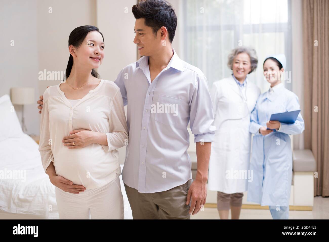 Donna incinta e marito con operatori sanitari Foto Stock