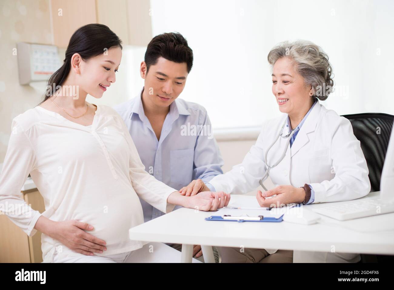 Il medico senior sente il polso della donna incinta Foto Stock