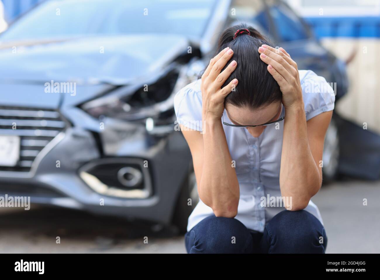 La donna spaventata si siede di fronte al closeup auto relitto Foto Stock