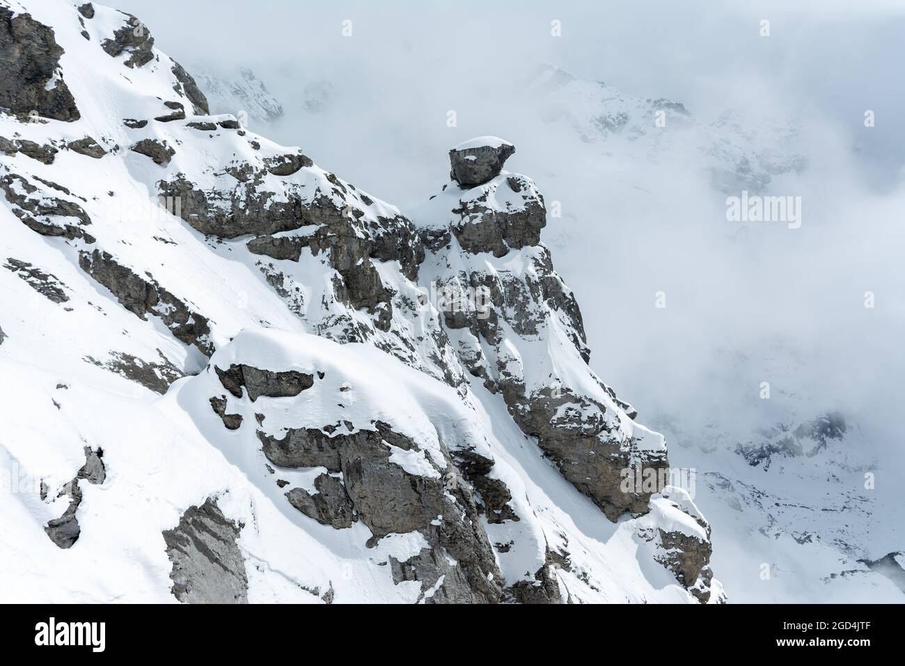 Vista di un tratto di montagna mentre la nebbia sale e copre la vetta del Monte Titlis a Engelberg, Svizzera. Picchi innevati. Foto Stock