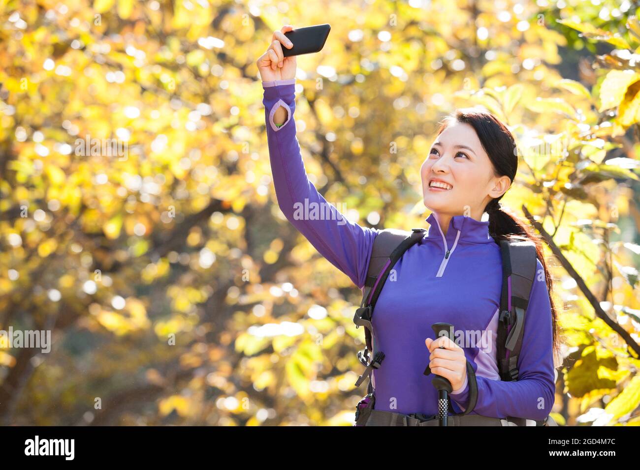 Felice donna zaino in spalla scattando foto con smartphone Foto Stock