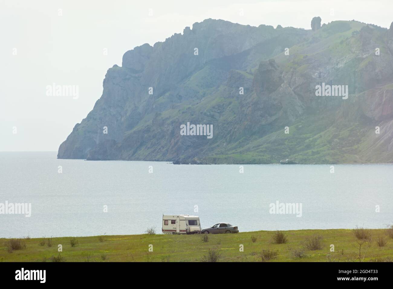 Crimea, il villaggio di Koktebel il 25 aprile 2021. Campeggio auto sulla spiaggia con una vista suggestiva del Kara-Dag. Un furgone con un rimorchio per una passe Foto Stock