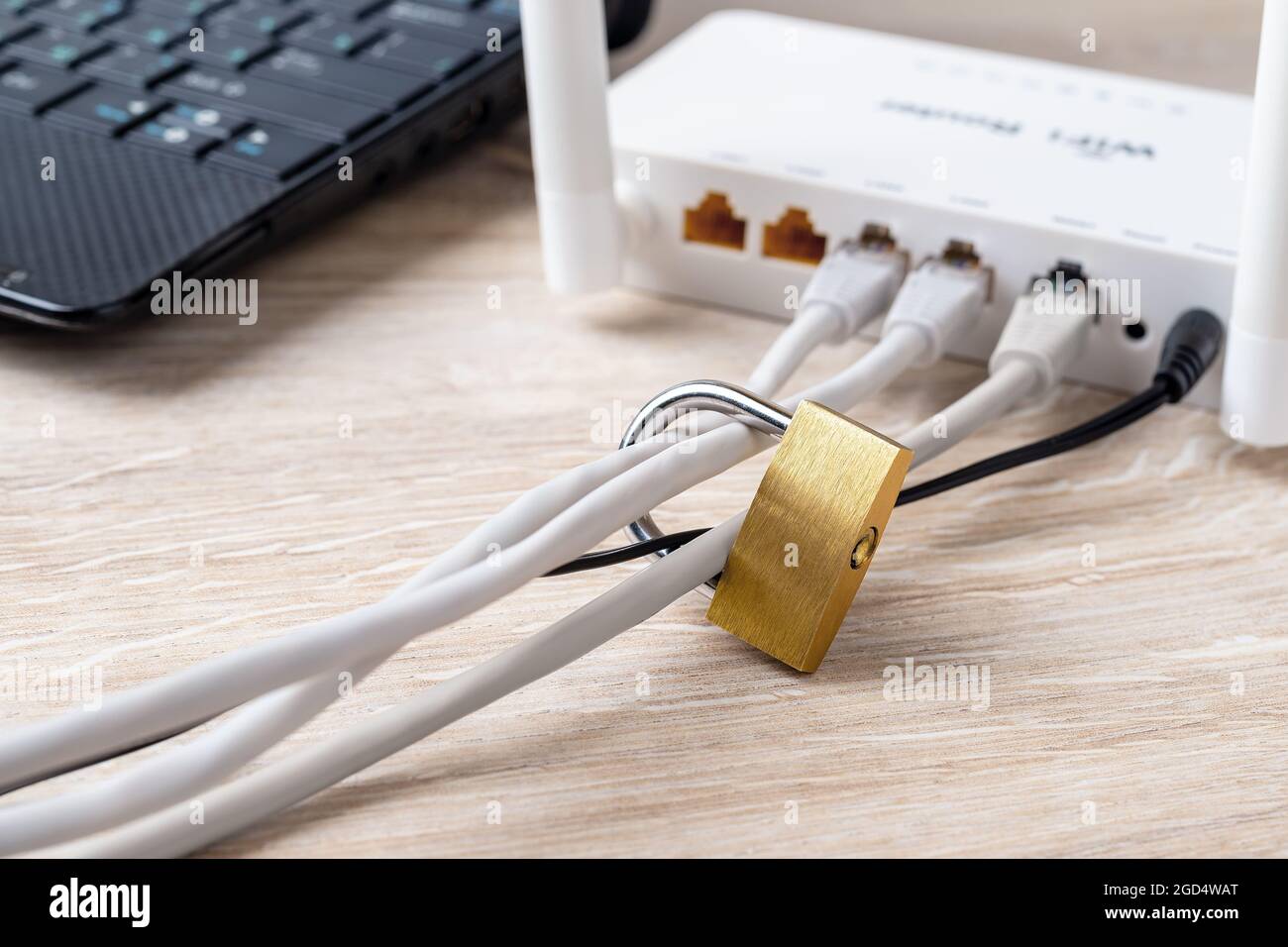 Lucchetto sui cavi di rete di un router Wi-Fi vicino al computer portatile sulla scrivania. Concetti di connessione Internet proibita o limitata e censura di Internet. Foto Stock