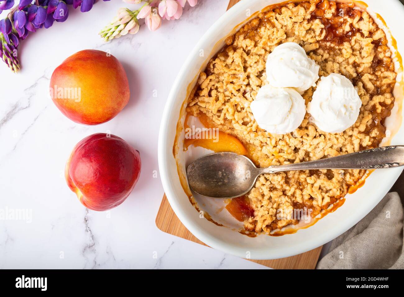Fresco nettarine fatto in casa crumble con gelato alla vaniglia in forma ceramica su sfondo di marmo bianco. Vista dall'alto. Foto Stock