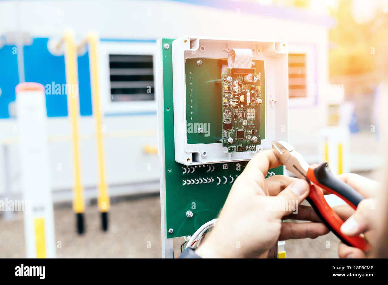 Regolazione dell'apparecchiatura di controllo e misurazione. Le mani di un elettricista o di un ingegnere con pinze al lavoro da vicino. L'appaltatore esegue i lavori nello stabilimento di produzione. Foto Stock