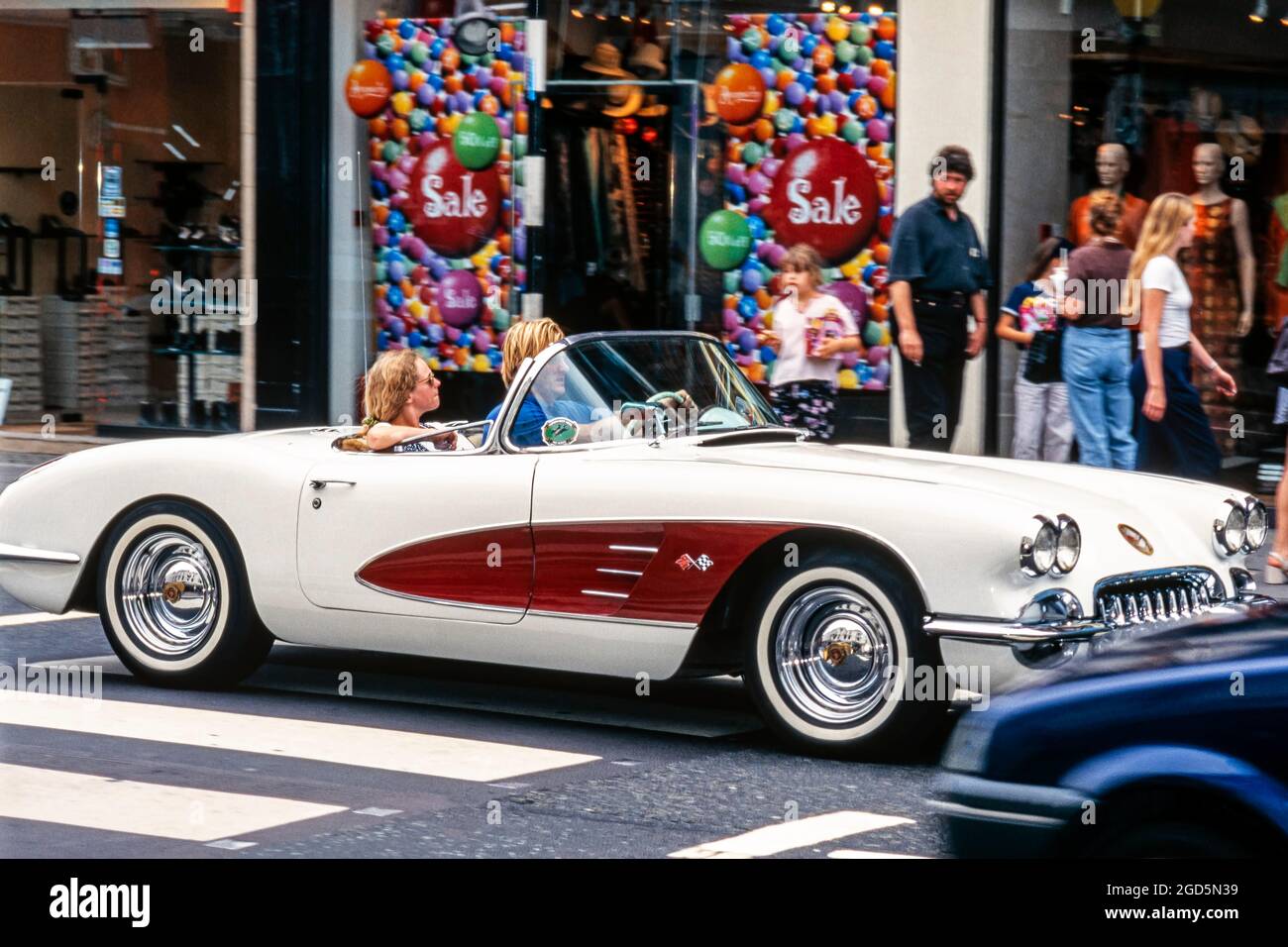 Chevrolet Corvette convertibile C1 1956 passando per negozi e pedoni su King's Road, Chelsea, Londra, Inghilterra, Regno Unito Foto Stock