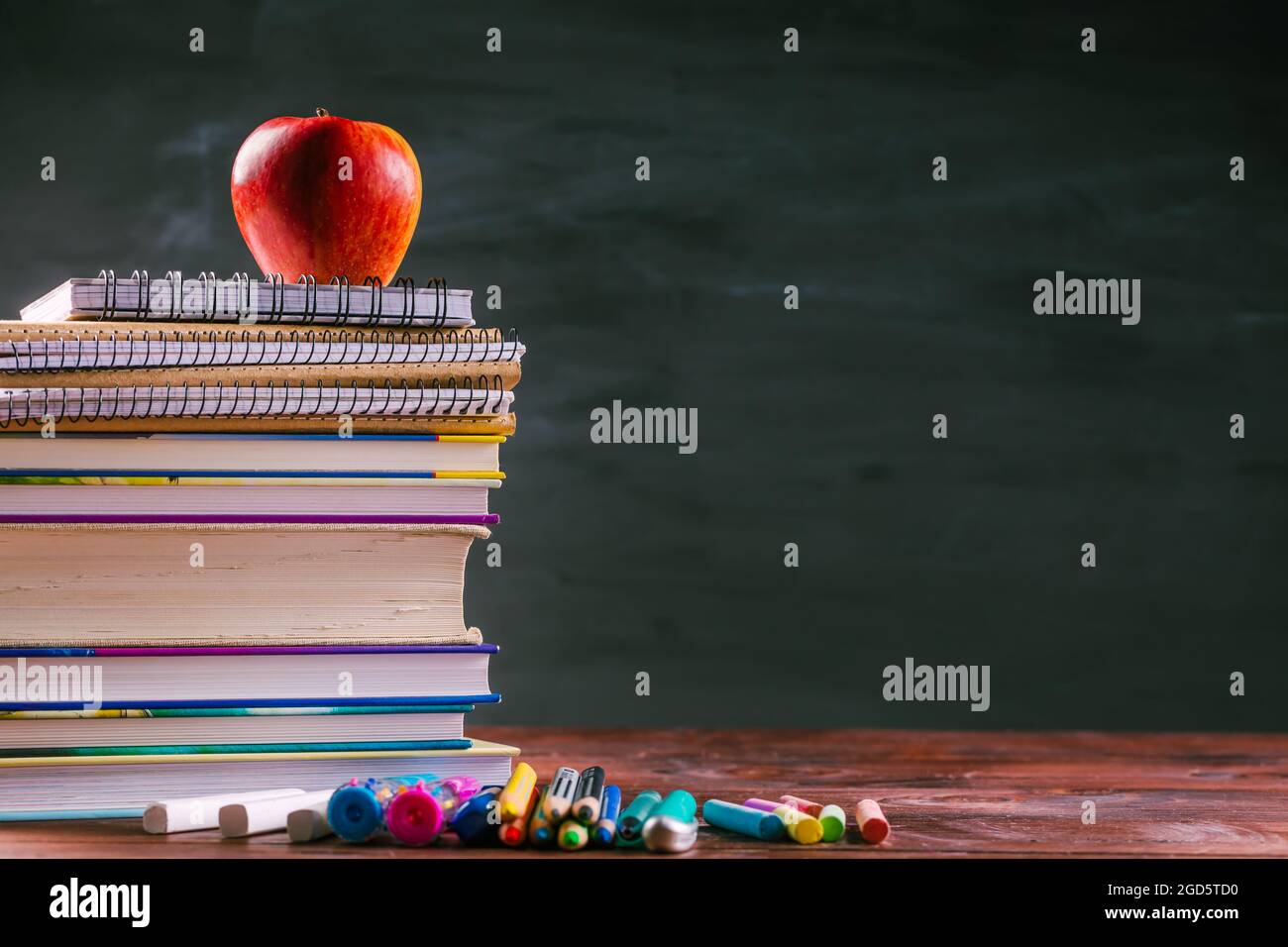 Mucchio di libri e libri di esercizi con shool si applica e spuntino di mela con lavagna. Concetto di ritorno a scuola. Foto Stock