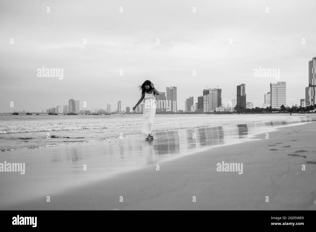 Affascinante giovane donna asiatica in abito bianco camminando sulla spiaggia. Romantica foto in bianco e nero. Foto di alta qualità Foto Stock